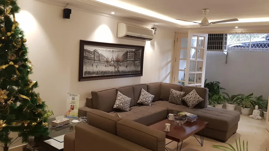 The reception and waiting area at Orion Dental Clinic, with a sofa, a framed painting and plants